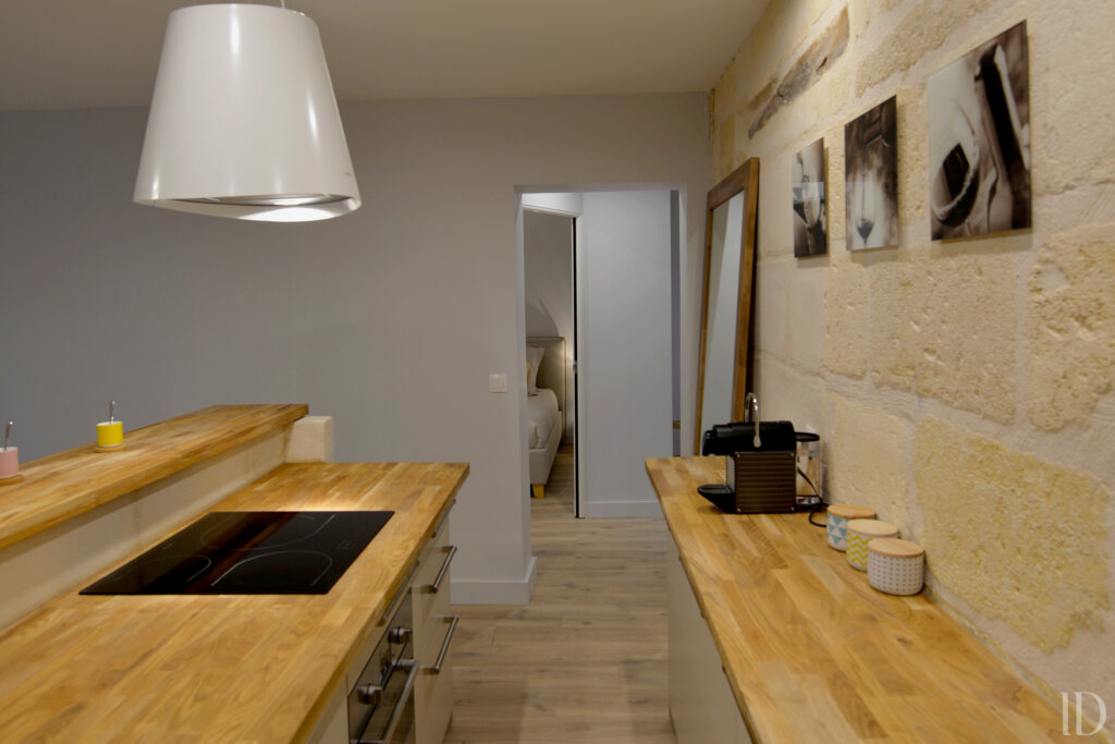 Rénovation d'un appartement à Bordeaux centre pour adaptation en établissement de nuit. Réalisation d'un espace cuisine ouvert sur le séjour avec mur en pierre apparente préservé.